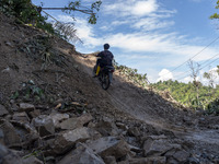 A motorist walks on the Trans Palu-Kulawi Road which is buried by landslide material in Namo Village, Sigi Regency, Central Sulawesi Provinc...