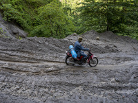 A rider ride oxygen cylinders across the Palu-Kulawi Trans Road which was buried by landslide material in Namo Village, Sigi Regency, Centra...