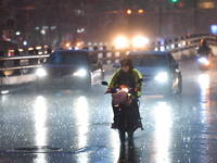 People wearing a raincoat ride a motorcycle in the rain on September 1, 2021 in Bangkok, Thailand. (