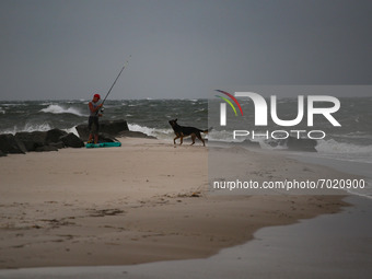 A man and his dog leave a beach as remnants of Hurrican Ida hit Cape May Point, New Jersey, the southern-most tip of the state on September...