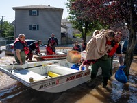 Resident Maria Tiraco of Lodi, New Jersey is helped from a boat after being rescued by the Lodi Fire Department following torrential rains a...