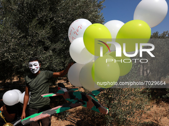 Masked Palestinian supporters of the Hamas movement prepare balloons with “Save Gaza” slogans written on them, near Jabalia refugee camp, ea...