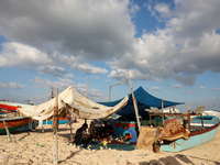 Palestinian fishermen mend their nets along a beach in Khan Yunis, southern Gaza Strip, on September 6, 2021. (