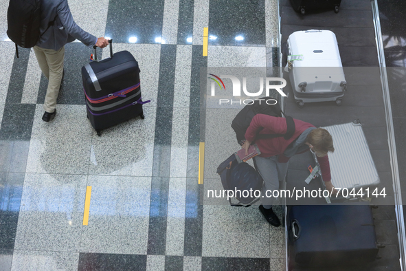 A male passenger wearing protective mask collects his bag after arriving on flight SQ 325 from Frankfurt at Changi International Airport on...