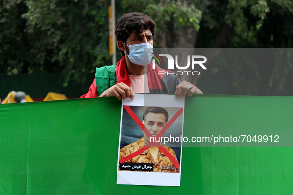 An Afghan national residing in India holds a poster of ISI chief Faiz Hameed during a demonstration against Pakistan's alleged support to th...