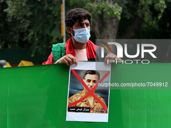 An Afghan national residing in India holds a poster of ISI chief Faiz Hameed during a demonstration against Pakistan's alleged support to th...