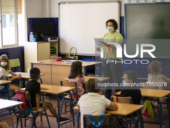 A teacher with a face mask talks to the students in a classroom during the new opening of the Primary School Year at CEIP Mariana Pineda Pub...