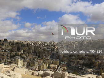 The sun illuminates part of the city and the national flag of Jordan. Amman, Jordan, Saturday, September 11, 2021. (