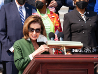 House Speaker Nancy Pelosi (D-NY) removes her mask before speaking during a ceremony in the Capitol steps in remembrance of the victims of t...