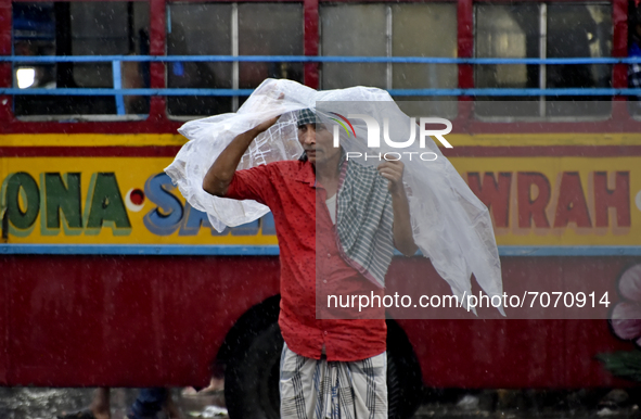 A migrant labour carries plastic as his shelter during heavy rainfall in Kolkata, India, 14 September, 2021.  