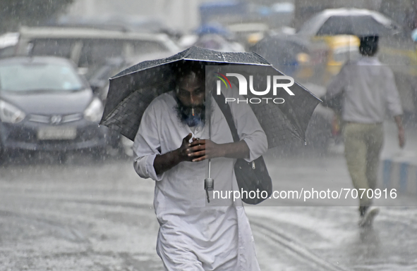 A man smokes while carries an umbrella during heavy rainfall in Kolkata, India, 14 September, 2021.  