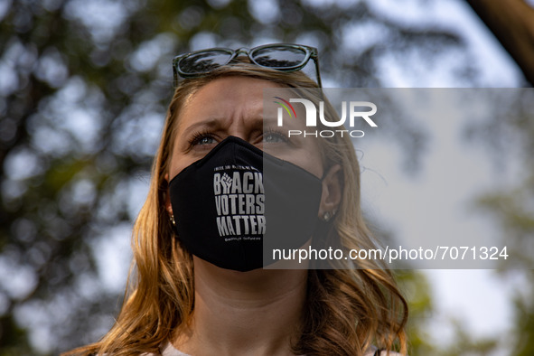 A woman wearing a 'Black Voters Matter' mask watches as members of Congress speak at the “Finish the Job: For the People” voting rights rall...