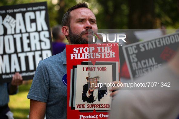 People watch and hold signs as members of Congress speak at the “Finish the Job: For the People” voting rights rally At the Robert A. Taft M...