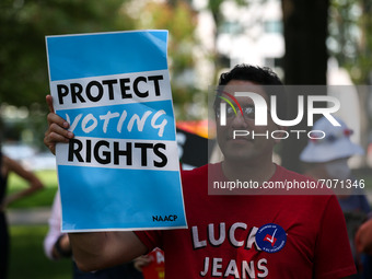 People watch and hold signs as members of Congress speak at the “Finish the Job: For the People” voting rights rally At the Robert A. Taft M...
