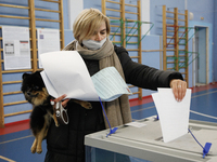 A woman with a dog at a polling station during voting in the State Duma of the Russian Federation in St. Petersburg. Saint Petersburg, Russi...