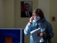 A woman at a polling station walks past a portrait of Russian President Vladimir Putin during a vote in the State Duma of the Russian Federa...