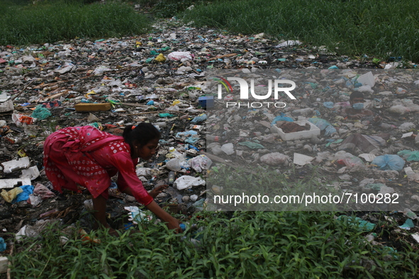 A woman collects plastic bottles from a canal to sell them to recycle factory in Dhaka, Bangladesh on September 19, 2021. Some two billion p...