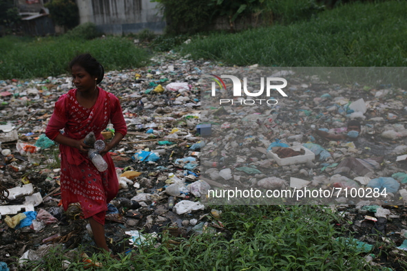 A woman collects plastic bottles from a canal to sell them to recycle factory in Dhaka, Bangladesh on September 19, 2021. Some two billion p...