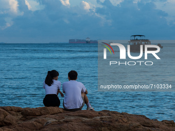A young couple enjoy the sunset in Stanley, in Hong Kong, China, on September 19, 2021. (