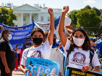 Two members of Communidades Organizando el Poder y la Acción Latina (COPAL) raises their fists in front of the White House during a march fo...