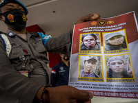 A police officer shows photos of the remaining four members of the Poso East Indonesia Mujahidin (MIT) Terrorist Search List (DPO) at the Ce...