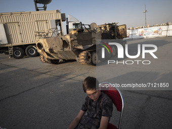 A young boy looks on as he sits near a military personnel carrier in a war exhibition which is held and organized by the Islamic Revolutiona...