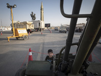 An Iranian young boy smiles as he poses for a photograph with an anti-aircraft gun in a war exhibition which is held and organized by the Is...
