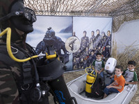 Young boys pose for a photograph in front of images of IRGC fighters while visiting a war exhibition which is held and organized by the Isla...