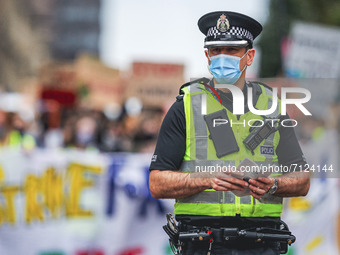 A police officer looks on as protesters take part in a climate protest as they march though the city centre on September 24, 2021 in Glasgow...