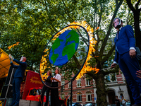 A group of activists is setting on fire a circle that represents the Earth, while they are dressing like politicians, during the Global Clim...