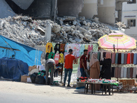 Women shop next to the rubble of destroyed buildings hit by Israeli airstrikes during an 11-day war between Gaza's Hamas rulers and Israel,...