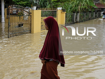 People are seen walking through floods caused by a river overflowing after heavy rains in North Aceh, on October 1, 2021, Aceh Province, Ind...