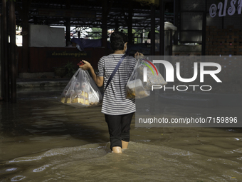 Villagers living in the Koh Kret area, Nonthaburi province have walked through the flood to buy food and snacks to stock up for eating, on O...