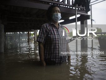 The owner of the house stood to see the height of the water that flooded the house from the Chao Phraya River, on October 1, 2021.  (