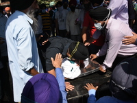 Sikh mourners sit around the dead body of the slain school principal Supinder Kaur in Srinagar, Indian Administered Kashmir on 8 October 202...