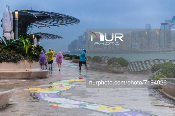  A group of youngsters in colorful plastic raincoats walk on Avenue of Stars in Tsim Sha Tsui, in Hong Kong, China, on October 9, 2021.  