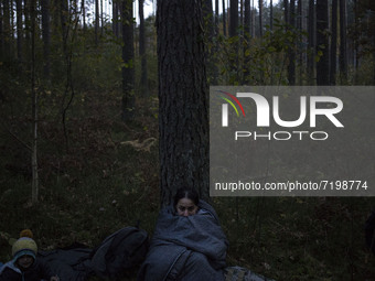 Illegal immigrant sits in sleeping bag after crossing polish belarusian border near Michalowo on October 6, 2021. (