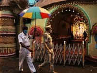 A Police man holding umbralla on the a senior police office a makeshift place of worship on the occasion of Durga Puja festival in Kolkata o...