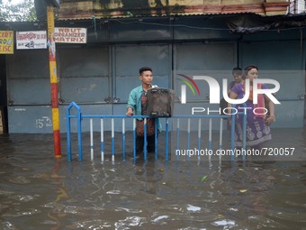 Indian people waiting for the transport in the waterlogged street in Kolkata , India on Wednesday , Aug. 5, 2015. 
 (