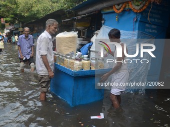 An Indian vender  running  his food stall  in the waterlogged street in Kolkata , India on Wednesday , Aug. 5, 2015.  (