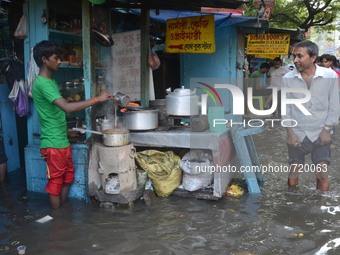 An Indian boy running  his tea stall  in the waterlogged street in Kolkata , India on Wednesday , Aug. 5, 2015.  (