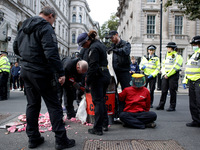 Police officers with cutting equipment work to remove Greenpeace activists 'locked-on' to oil drums outside the gates of Downing Street on W...