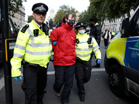 Police officers arrest a Greenpeace activist freed from being 'locked-on' to an oil drum outside the gates of Downing Street on Whitehall in...
