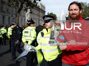 Police officers arrest a Greenpeace activist freed from being 'locked-on' to an oil drum outside the gates of Downing Street on Whitehall in...