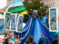 Allies carry signs and a puppet representing water while Native American activists lead a march from Freedom Plaza to the White House agains...