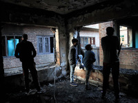 Kashmiri people assess the damaged residential house where a gunbattle took place between Indian forces and Kashmiri militants in Tulran vil...