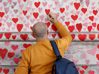A man writes a message onto the National Covid Memorial Wall on the south bank footpath of the River Thames opposite the Houses of Parliamen...