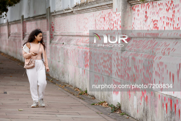 A young woman looks at the National Covid Memorial Wall on the south bank footpath of the River Thames opposite the Houses of Parliament in...