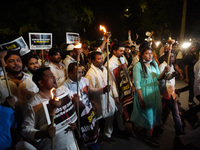 Activists of the Indian Youth Congress (IYC) party hold torches as they shout slogans during a protest against killing of four farmers in Ut...
