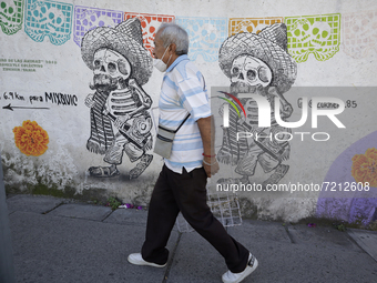 A passerby in front of a mural alluding to the Day of the Dead in the streets of downtown Santiago Tulyehualco (Xochimilco), Mexico City, du...